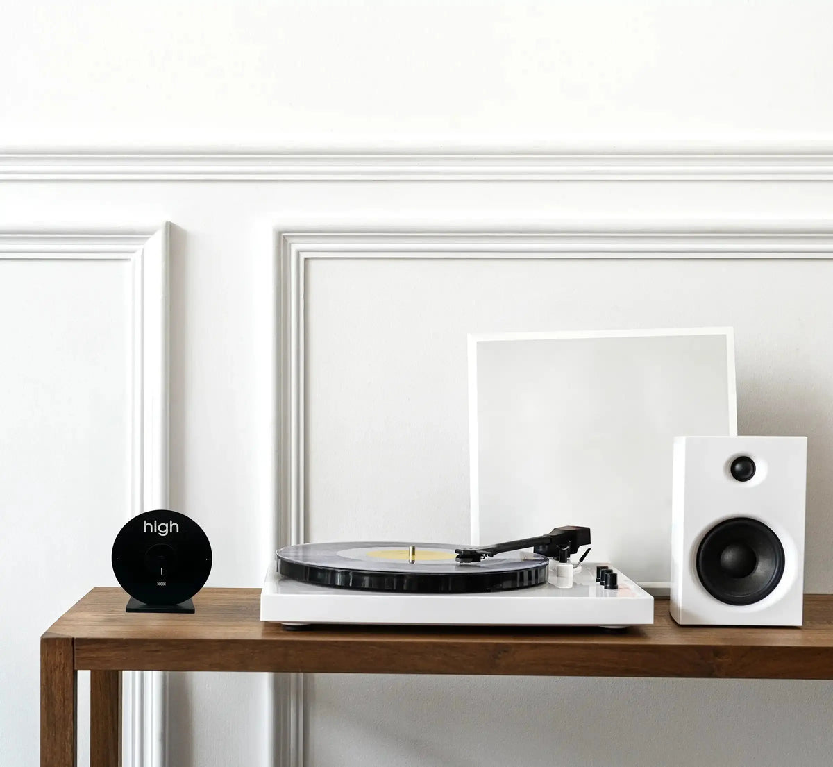table en bois avec desus : une horloge des marées, une platine disque vinyle et un baffle.