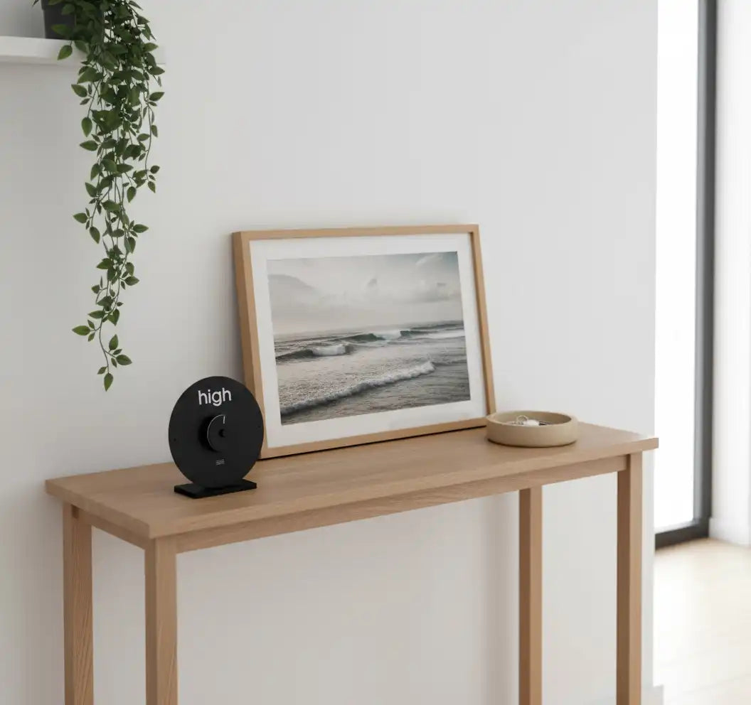 horloge des marées design posée sur une table à côté d'un cadre photo représentant une vague