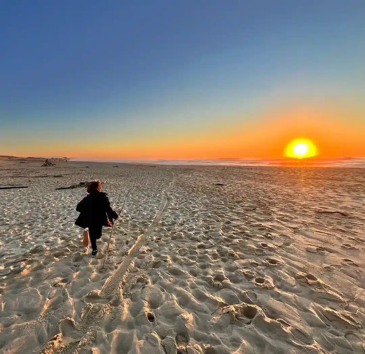enfant qui court sur une plage vers le soleil couchant