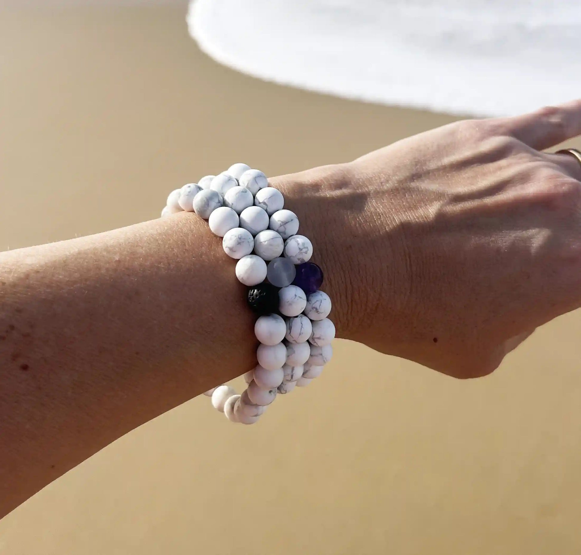 3 bracelets  de perles blanche porté au poignet 