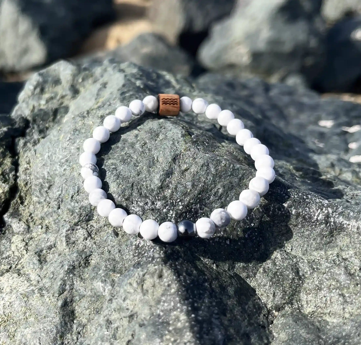 bracelet de perles blanche posé sur un roché