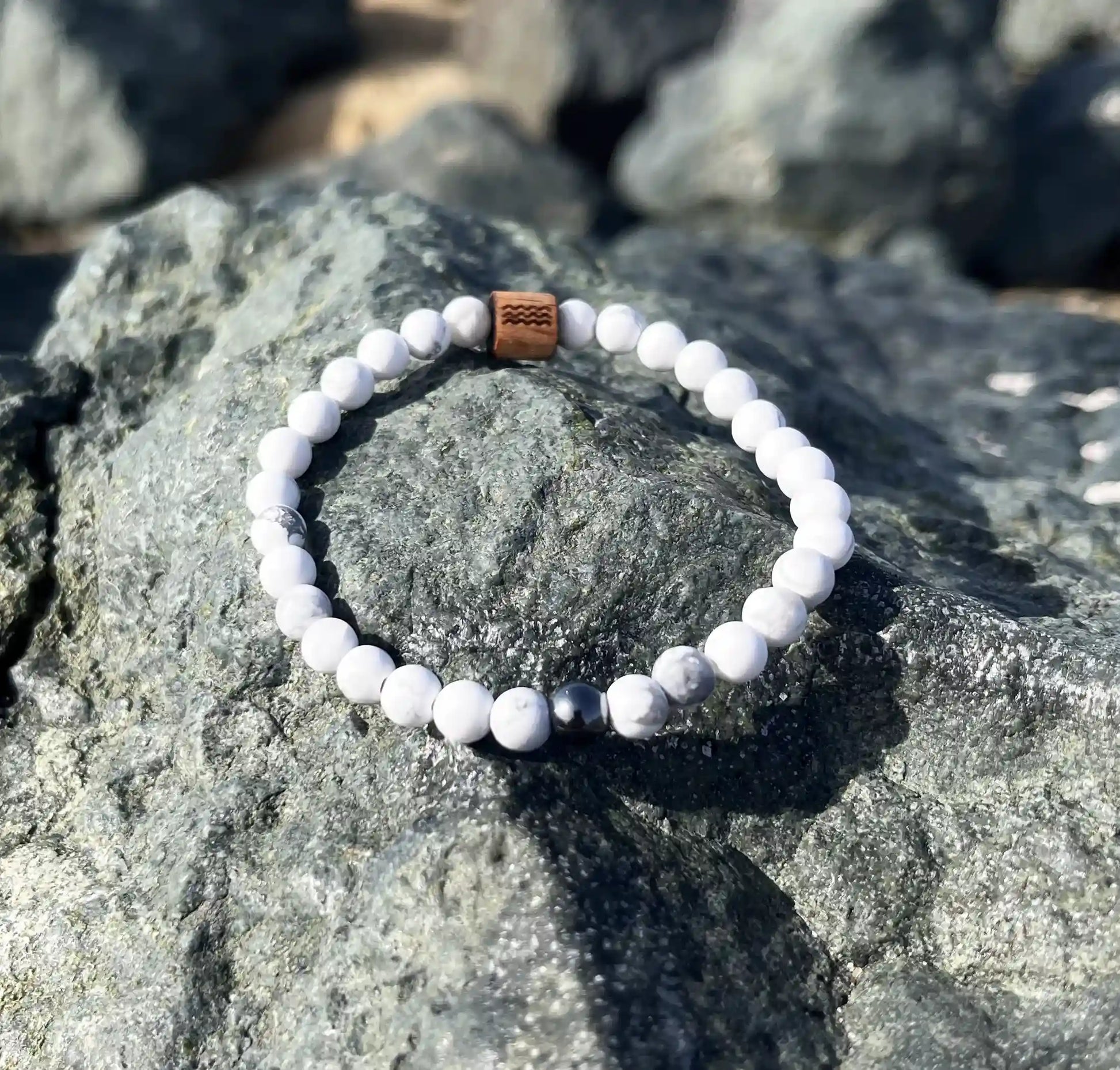 bracelet de perles blanche posé sur un roché
