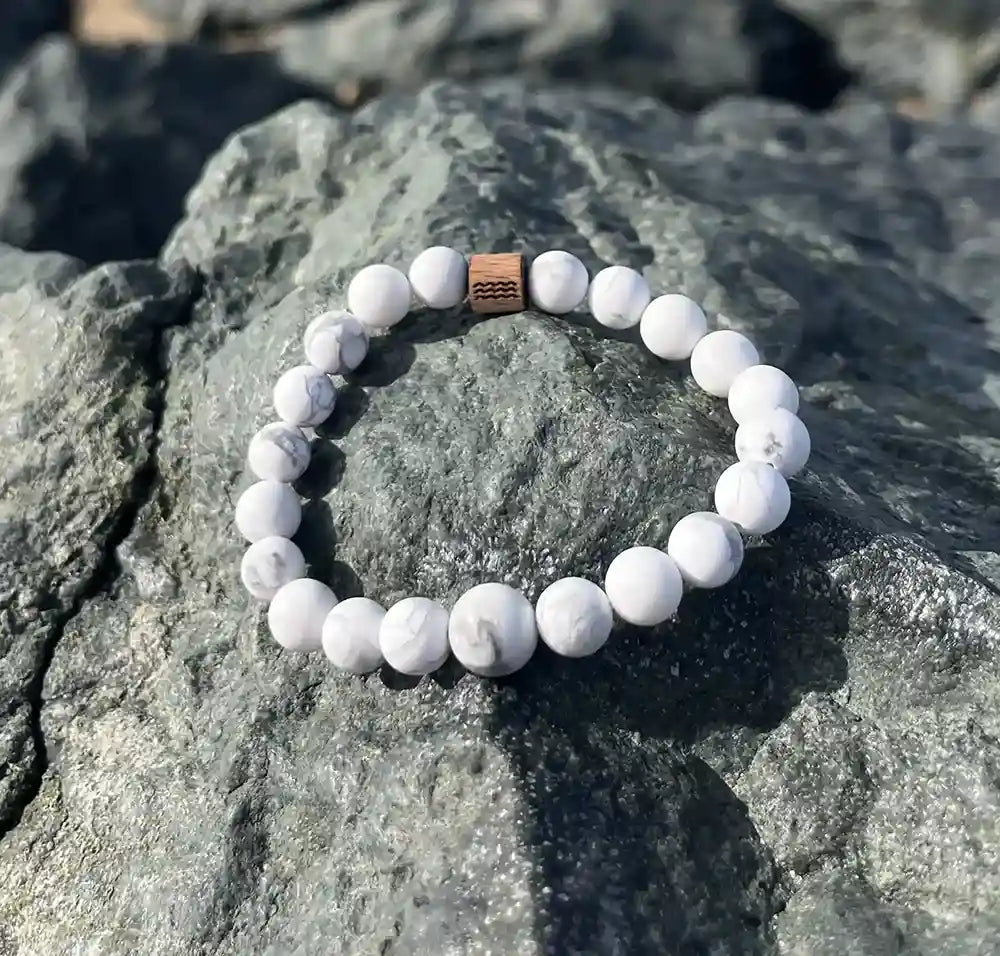 bracelet de perles blanche posé sur un roché