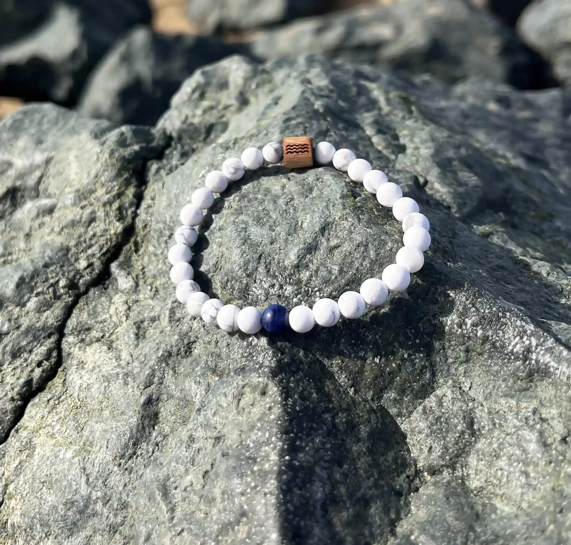 bracelet de perles blanche posé sur un roché