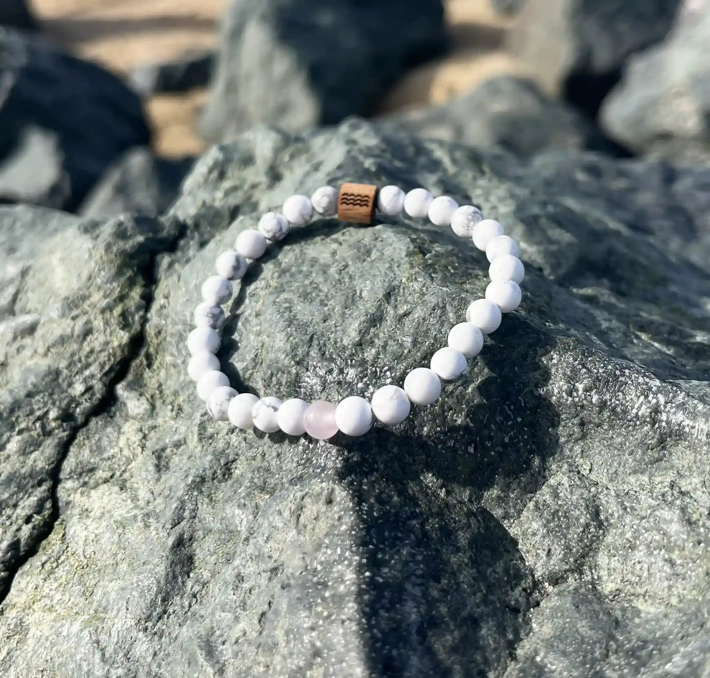 bracelet de perles blanche posé sur un roché