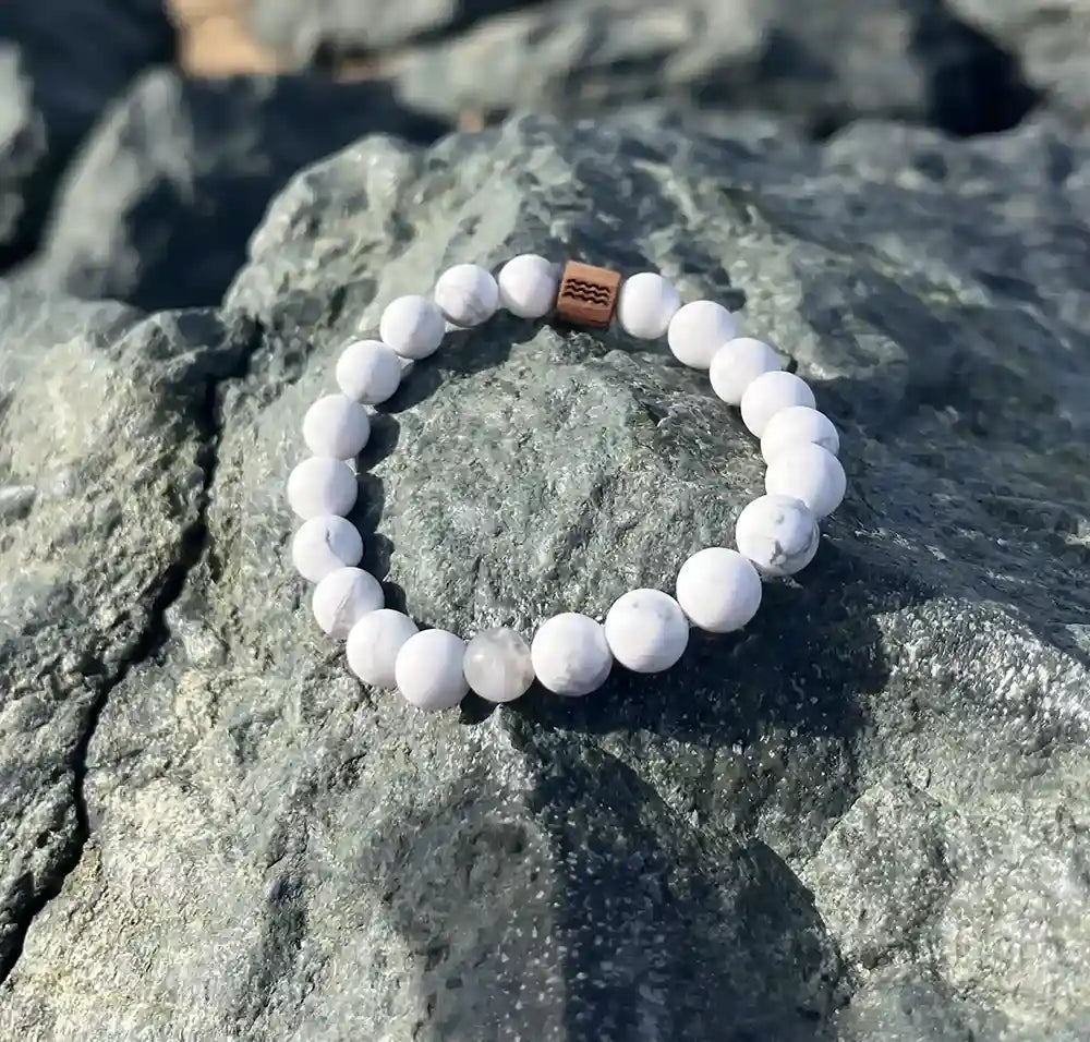 bracelet de perles blanche posé sur un roché