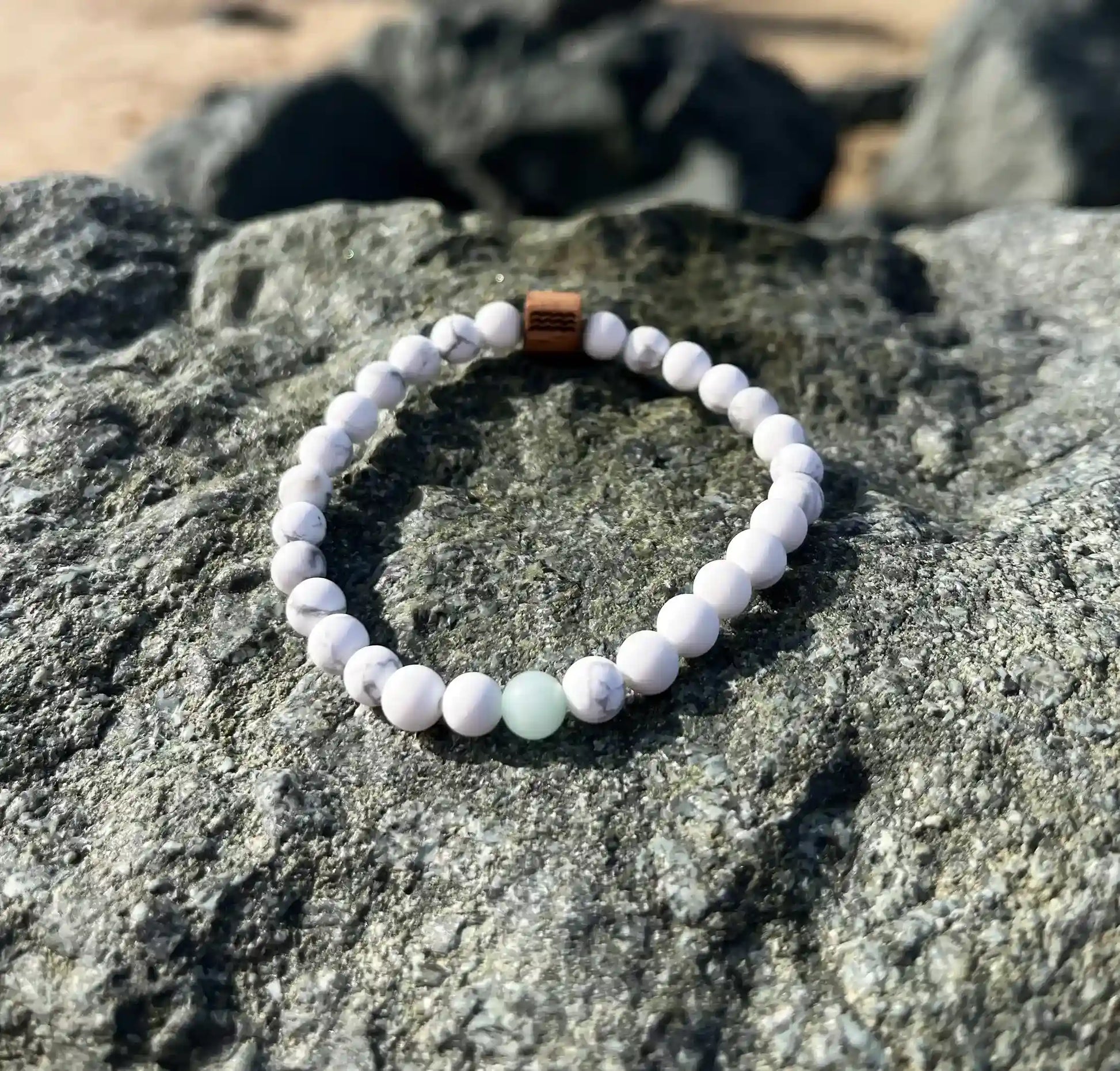 bracelet de perles blanche posé sur un roché