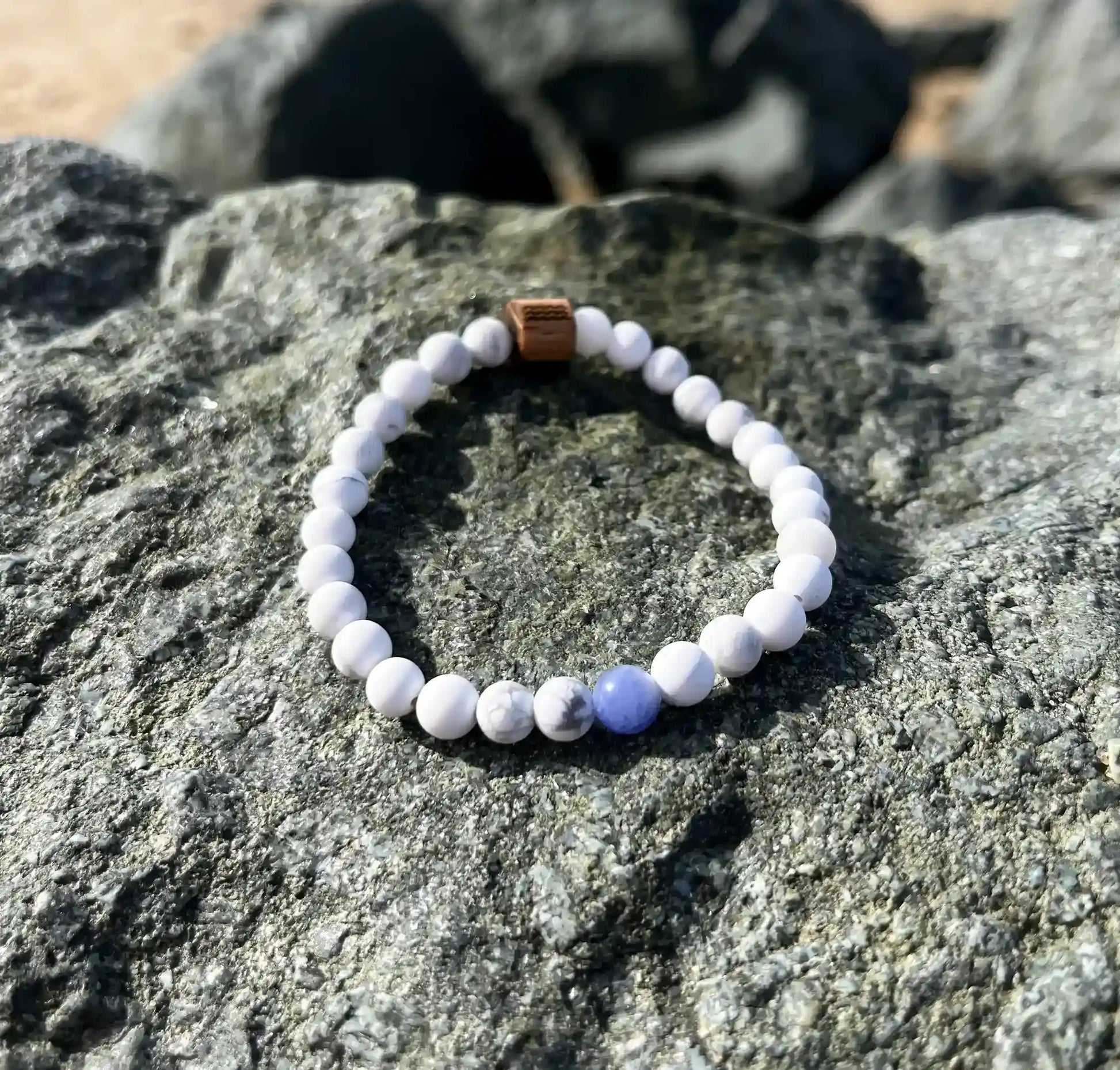 bracelet de perles blanche posé sur un roché
