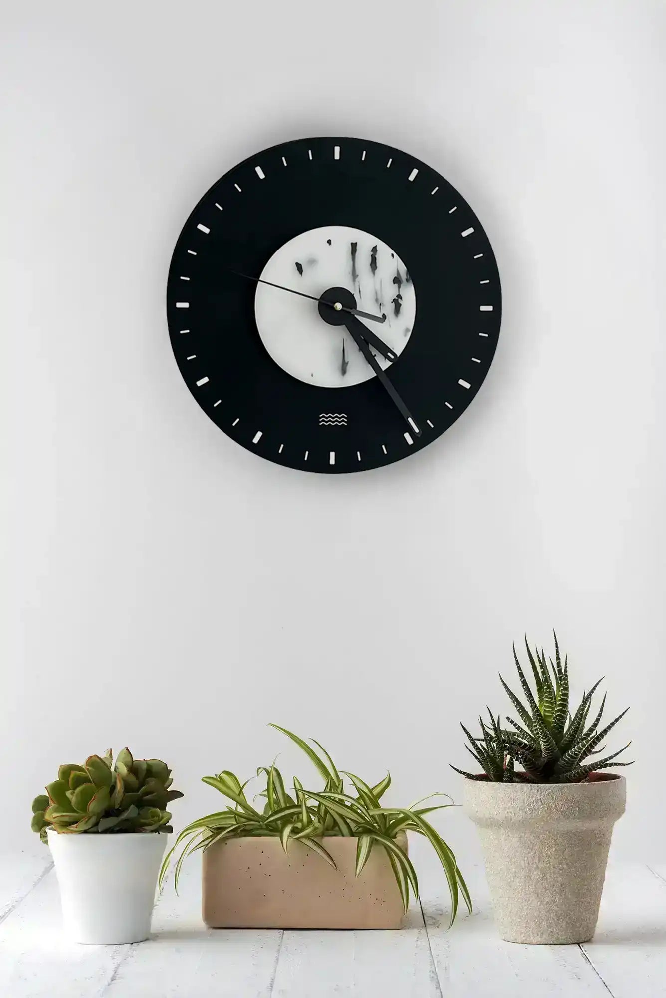 horloge noire et blanche au mur avec un avant plan de cactus
